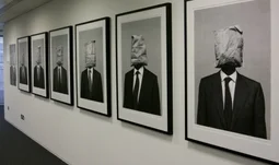 photographs on the wall of an office. The people have teabags for heads